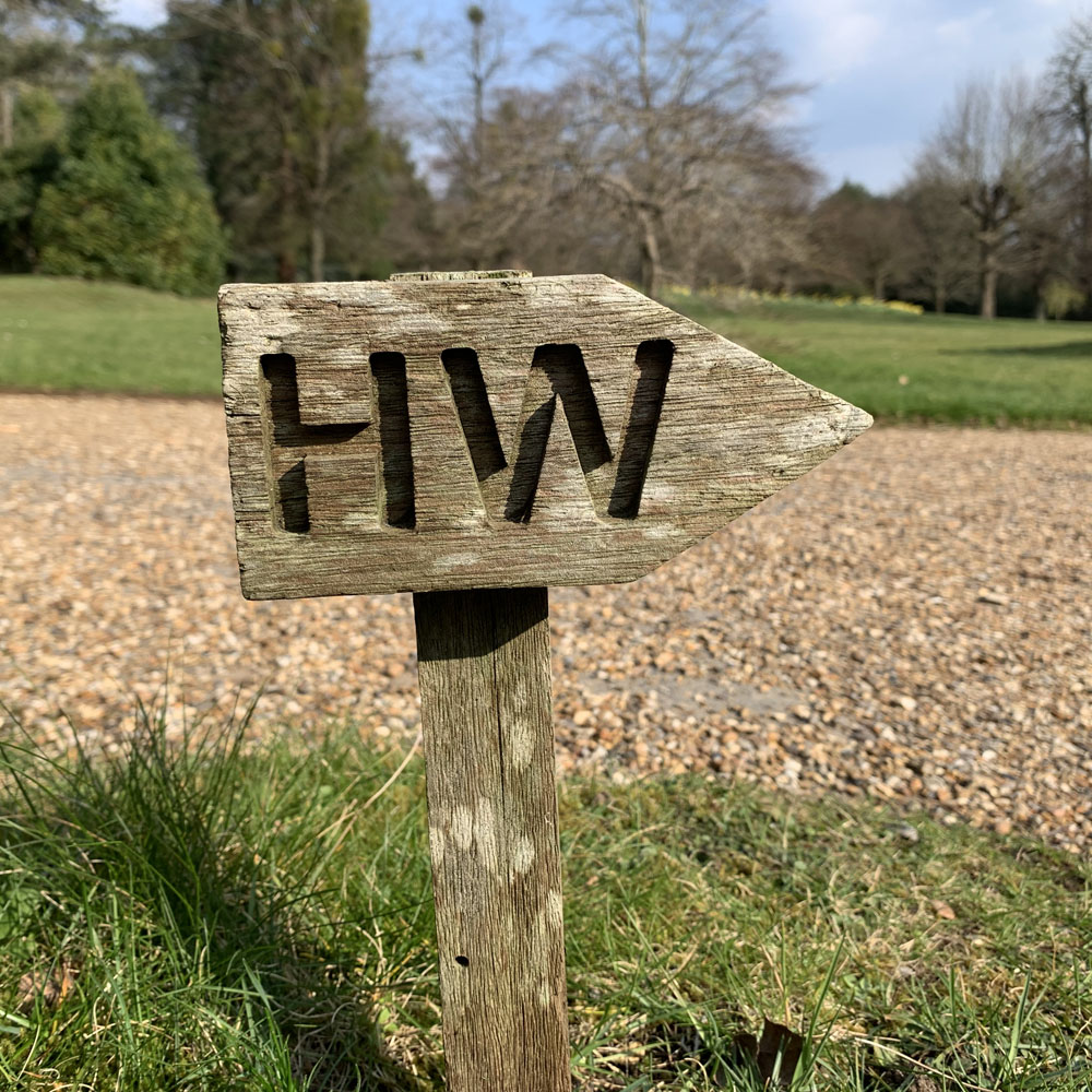 A wooden signpost, carved with the letters HW