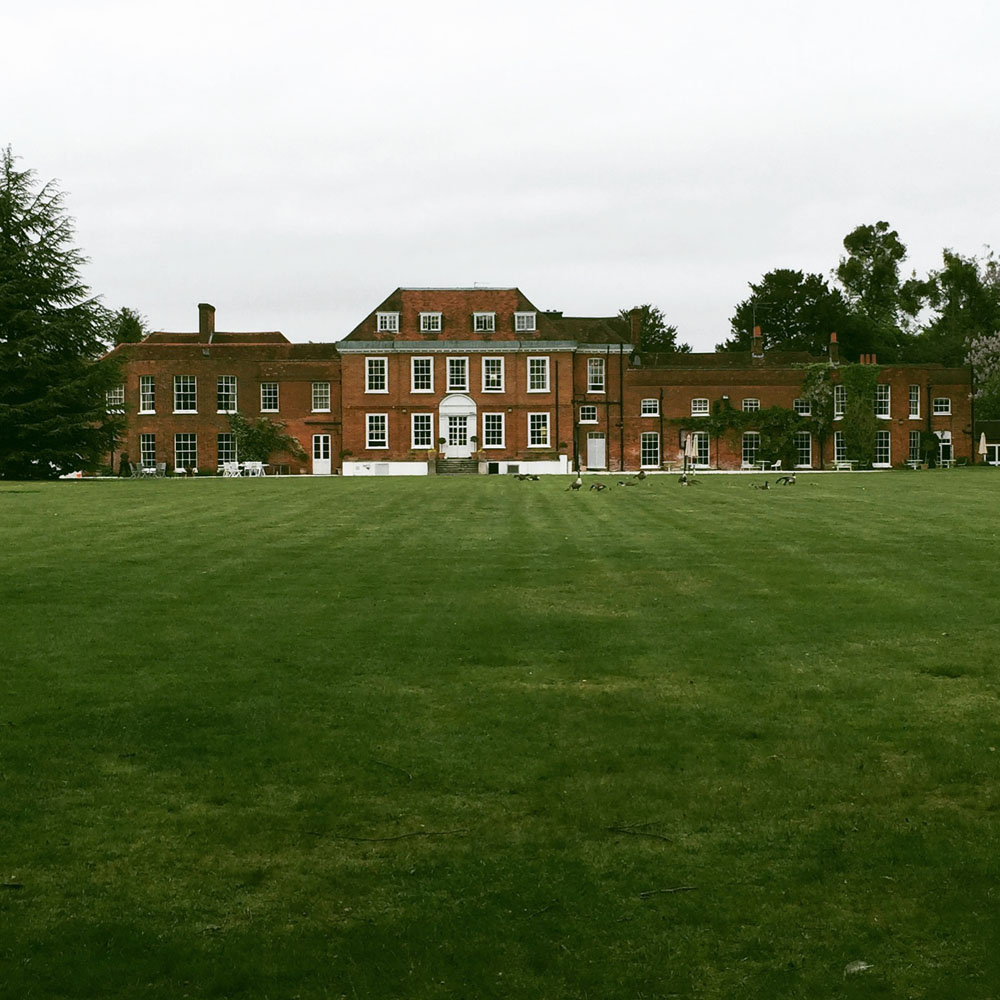 A large lawn in front of Stoke Place, surrounded by trees