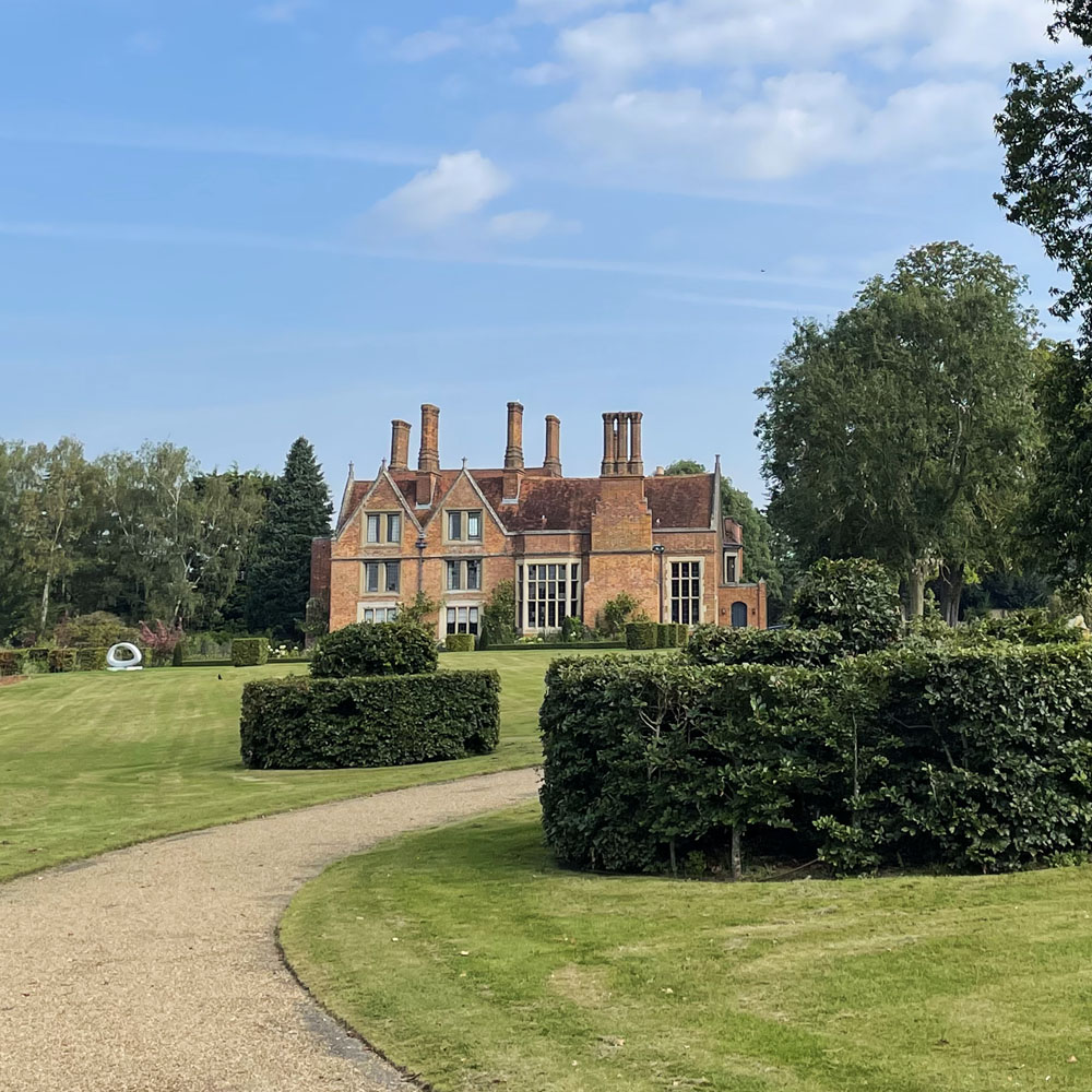 The Manor House with its tall chimneys, lawn, topiary and sculptures