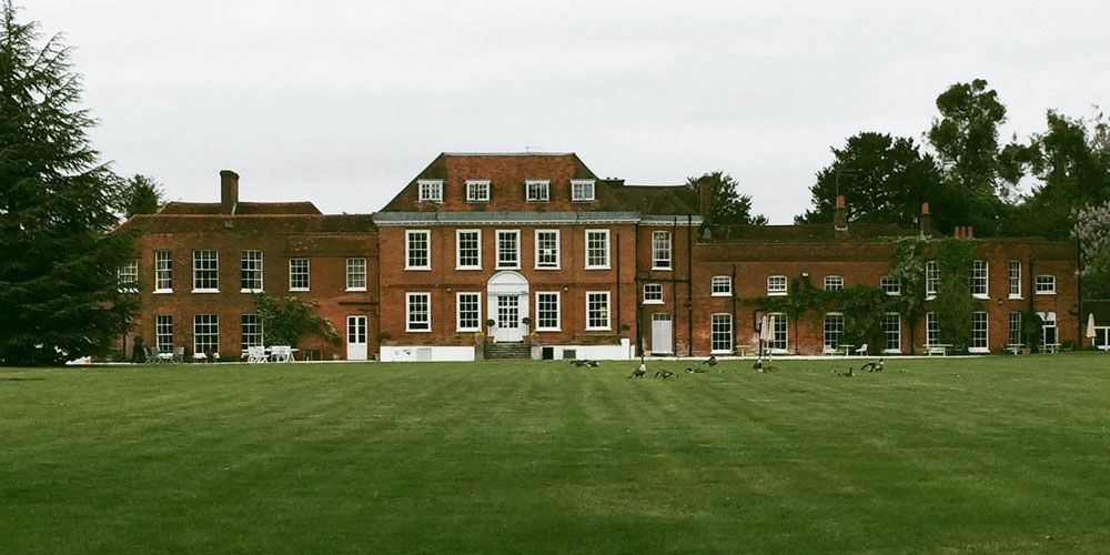 A large lawn in front of Stoke Place, surrounded by trees